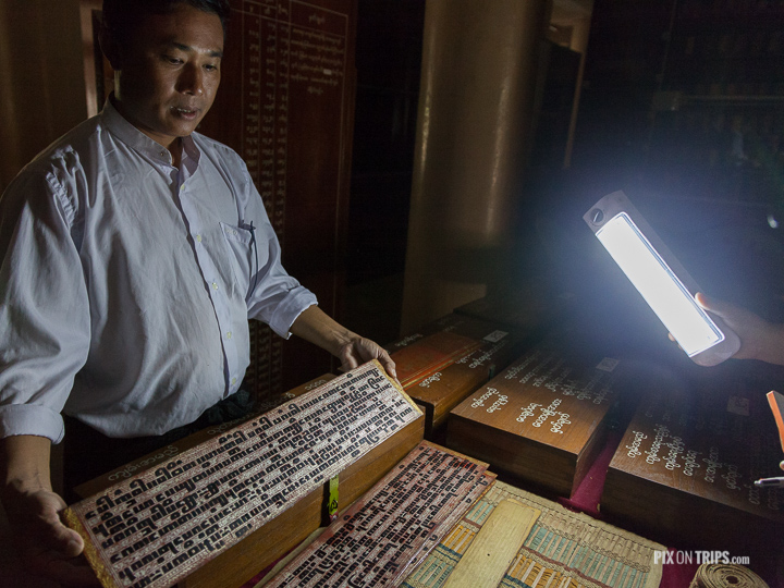 Guide at Shwe In Bin Kyaung monastery in Mandalay, Myanmar showing 500 year-old Buddist writings