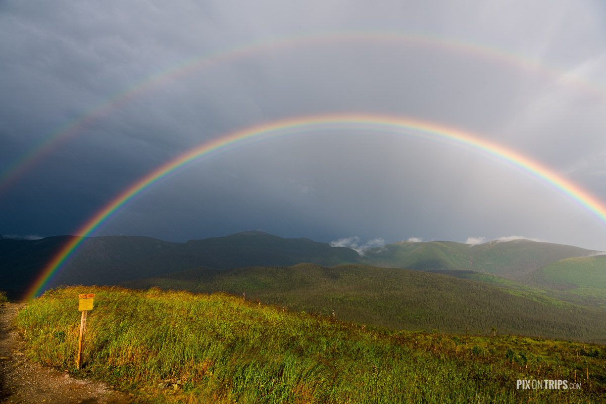 Rainbow at the summit of Mont Ernest Laforce in Parc National de la Gaspesie with mountain ranges in the background